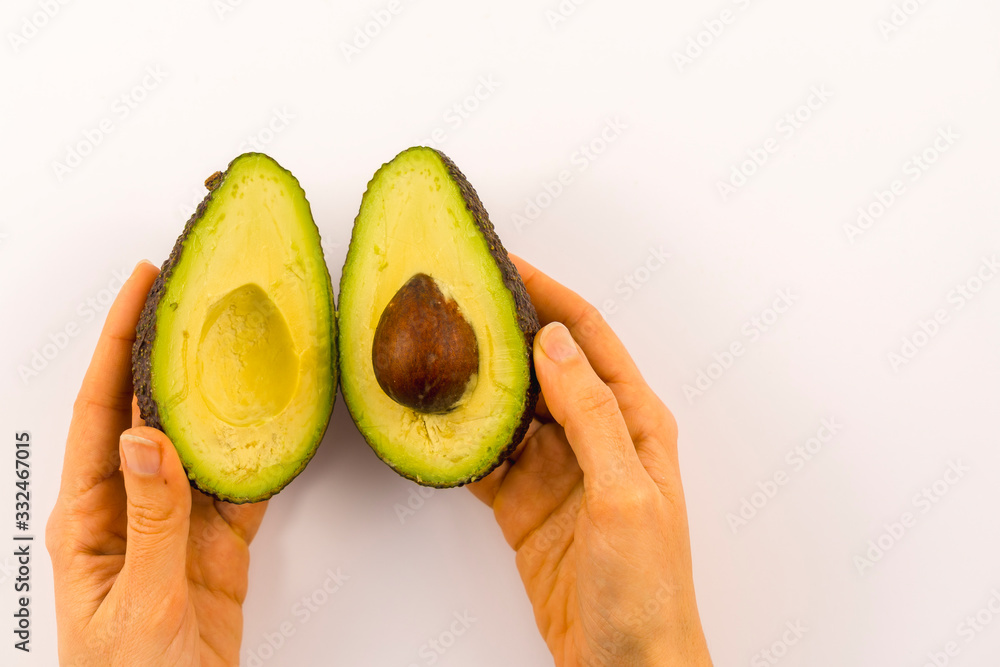 Wall mural Hands of a woman separating the avocado in two with copy space and paste. Recipe to prepare a nice guacamole