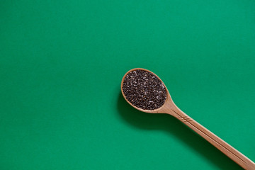 Chia seeds in wooden spoons. Superfood on a green background