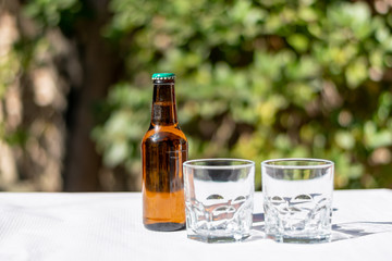 Two cristal glasses and one beer bottle on a white paper tablecloth.