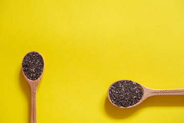 Chia seeds in wooden spoons. Superfood on a yellow background