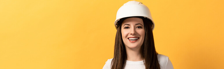 panoramic shot of smiling handywoman looking at camera isolated on yellow