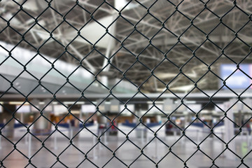 Worldwide coronavirus pandemic. Empty airport, check-in area  behind steel mesh wire fence. Flight ban and closed borders for tourists and travelers. Concept