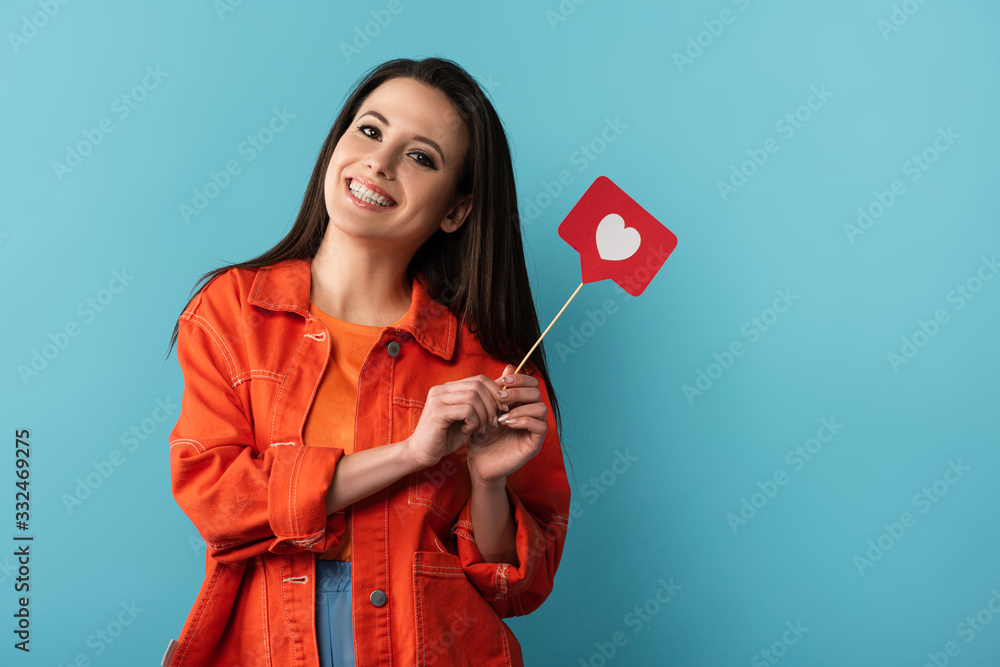 Wall mural smiling woman holding stick with paper like on blue background