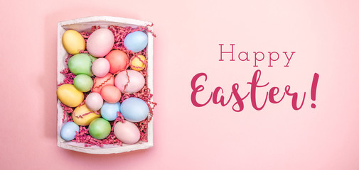 Multicolor eggs in a white tray. Creative Easter concept. Modern solid pink background. Horizontal, wide screen banner. Living coral accent, color of the year 2019