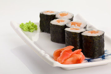 Japanese Cuisine - Appetizing Salmon Sushi Set. Philadelphia Sushi Roll - Maki Sushi with Philadelphia Cheese inside on mirror black background. Smoked salmon rolls served on a plate