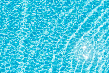Surface of blue shining swimming pool water ripple and sun reflection. Perfect as a background for summer, vacation, calmness, serenity or any other idea.