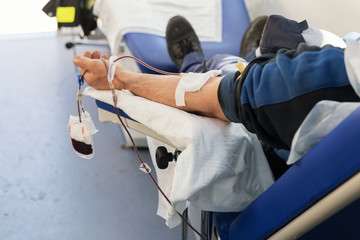 A hand of donor sitting on an armchair in a mobile blood bank during of blood collection. Donation...