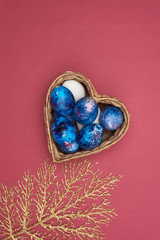  Happy Easter. Basket with Easter eggs and a golden branch on a purple background.