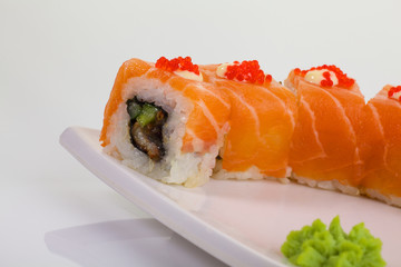 Japanese Cuisine - Appetizing Salmon Sushi Set. Philadelphia Sushi Roll - Maki Sushi with Philadelphia Cheese inside on mirror black background. Smoked salmon rolls served on a plate