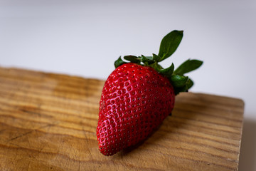 Fresh strawberry isolated on wooden cutting board and white background.