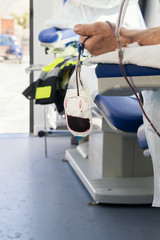 A hand of donor sitting on an armchair in a mobile blood bank during of blood collection. Donation...
