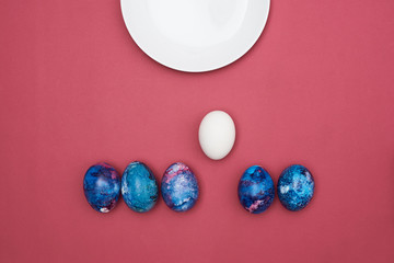  Easter eggs painted blue and a white plate. Burgundy background.