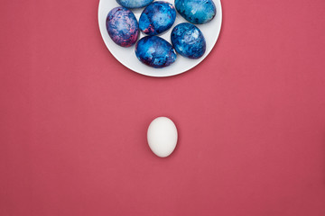  Easter painted colorful eggs in a white plate. Purple background. Top view.