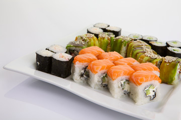 Japanese Cuisine - Appetizing Salmon Sushi Set. Philadelphia Sushi Roll - Maki Sushi with Philadelphia Cheese inside on mirror black background. Smoked salmon rolls served on a plate