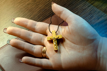 A small crucifix in a female hand. Pectoral crucifix on a female palm