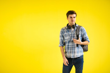 young man with backpack and headphones on yellow