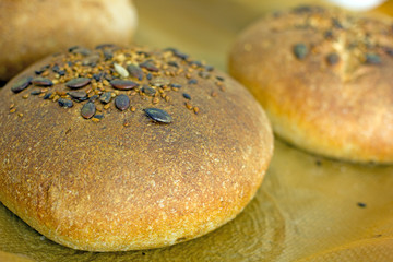 Cereal bread sprinkled with sesame seeds on top on parchment paper. Background about homemade bread, a loaf of whole grain bread