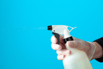 Man's hand in rubber glove sprays disinfectant.
