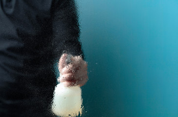 Man in rubber glove sprays disinfectant on a glass, selective focus.