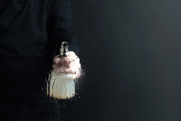 Man in rubber glove sprays disinfectant on a glass, selective focus.
