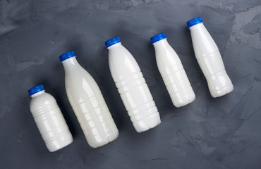 Collection of milk bottles on gray stone background, top view
