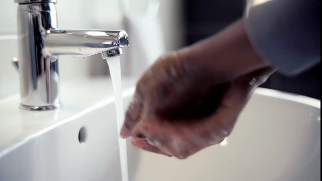 Closeup of African American woman washing hands in faucet