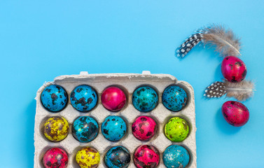 Easter composition with quail eggs and various feathers on a blue background. Greeting card. Flat lay. Copy space for text