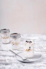 Overnight oats with yogurt topped with chocolate chips on the white wooden table