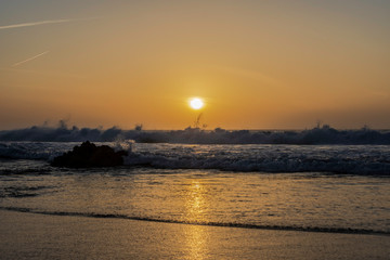 olas con viento en atardecer con sol y cielo dorado