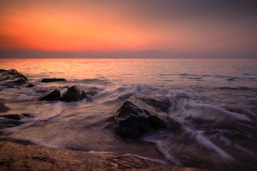 Sunrise at sea. Stones, waves and the sun. Seascape.