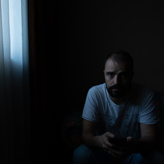 Naklejka na ściany i meble portrait of a man on a dark place with curtain 