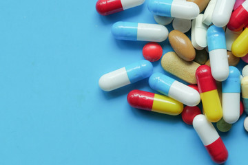  colorful pills spilling on blue background, top view