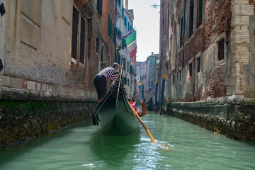 Fototapeta na wymiar San Marco / Venice / Italy - April 17, 2019: Tourists in gondola ride in the historic city of Venice in Italy. Small canal
