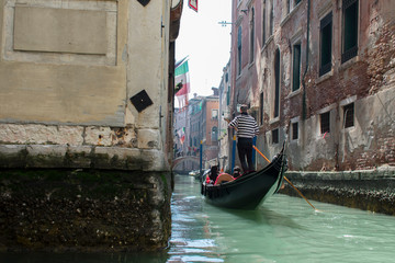Fototapeta na wymiar San Marco / Venice / Italy - April 17, 2019: Tourists in gondola ride in the historic city of Venice in Italy. Small canal