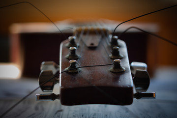 Head, tuners and strings of acoustic guitar lying on a table on the sheets of the piece of music