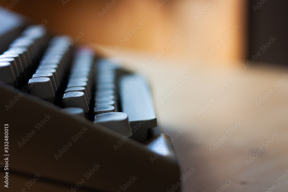 Fototapete old typewriter keyboard on a wooden table. side view. space for text. warm colors. creative writing.