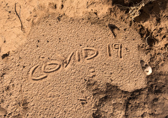 Corona virus name written in sand