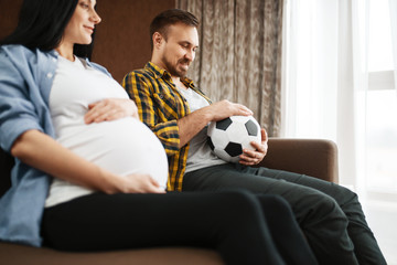 Husband with ball and his pregnant wife with belly