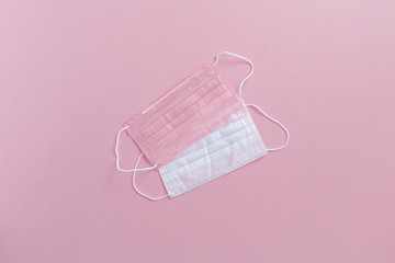 Pink protective surgical face mask and woman hands in gloves background, selective focus