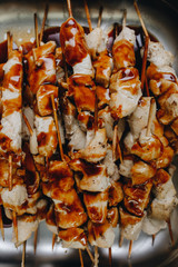 pieces of chicken in a sauce on wooden skewers. close up
