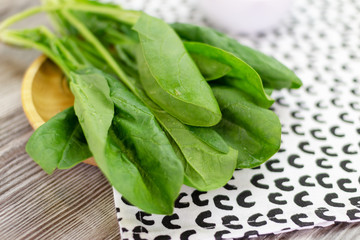 Fresh spinach lies on an interesting towel. Close-up