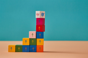 Business and career development. Goal achievement. Colorful blocks stack with marketing signs and crown, target on top