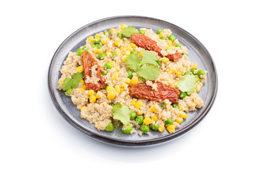 Quinoa porridge with green pea, corn and dried tomatoes on ceramic plate isolated on white background. Side view.