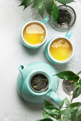 Two cups of green tea with a teapot on a gray concrete background with copy space. Top view
