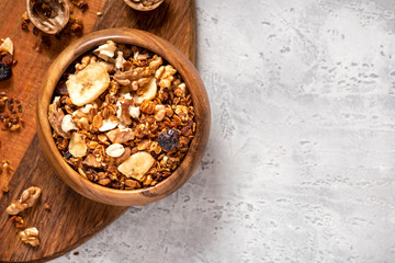Homemade toasted granola with honey, walnuts, flax and sesame seeds in a wooden bowl on a concrete...