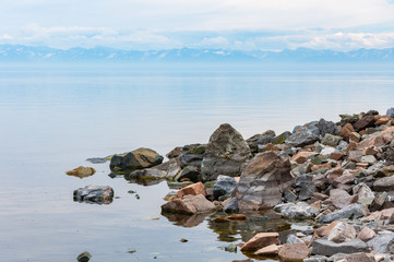 Lake Baikal shore with boulders and mountains on the horizon