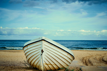 Lonely boat lying on the sand beach at the coast of the island usedom, Germany, under a blue and...