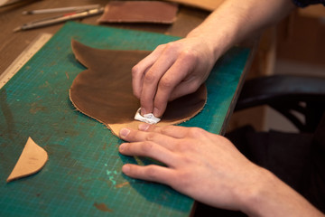 The man is dyeing leather. Close up of craftsman hands dyeing natural leather. Working process of leather craftsman.