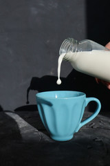 Jet of milk poured glass cup over black background