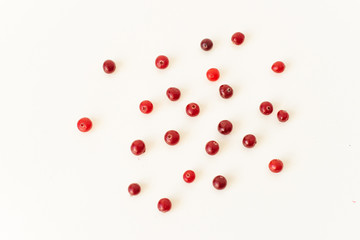 A scattering of cranberry berries on a white plate and table. Healthy food. Prevention and treatment of the disease.